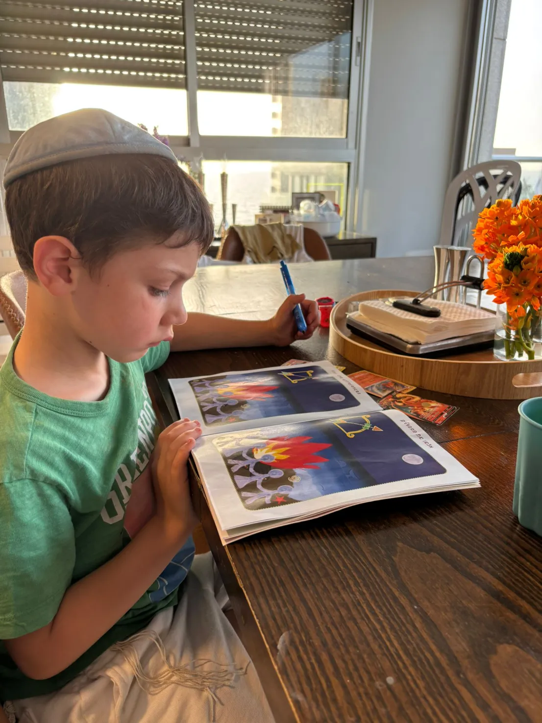 Boy reading Chodesh Magazine at the table